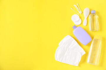 Baby accessories and cosmetic products on yellow background, flat lay. Space for text