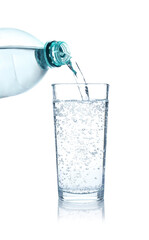 Pouring refreshing soda water from bottle into glass on white background