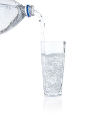Pouring refreshing soda water from bottle into glass on white background