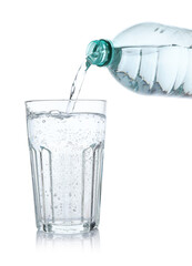 Pouring refreshing soda water from bottle into glass on white background