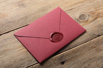 Envelope with wax seal on wooden table, above view