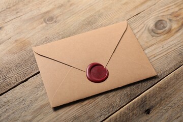 Envelope with wax seal on wooden table, above view