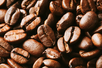 Closeup of roasted coffee beans background. Brown aromatic grains with texture. Fresh natural caffeine ingredient for hot drinks. Perfect energy booster for espresso cappuccino latte and black coffee.
