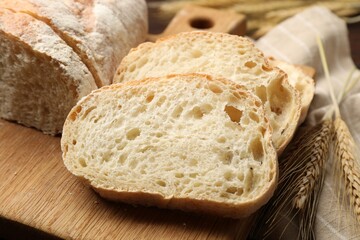 Fresh bread and wheat spikes on table, closeup