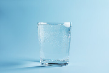 Refreshing soda water in glass on light blue gradient background, closeup
