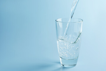 Pouring refreshing soda water into glass on light blue gradient background, closeup. Space for text