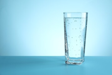 Refreshing soda water in glass on table against turquoise gradient background, closeup. Space for text