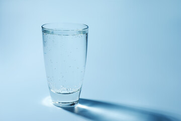 Refreshing soda water in glass on light blue background, closeup. Space for text