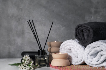 Spa composition with burning candles on white wooden table near grey wall