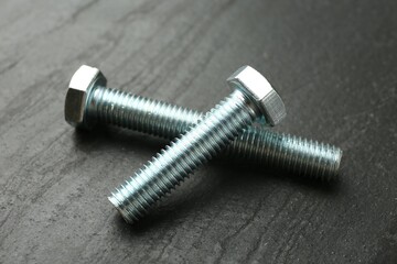 Two metal bolts on black table, closeup