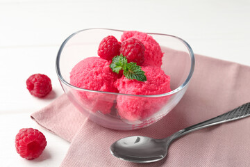 Delicious raspberry sorbet with mint in bowl, spoon and fresh berries on white wooden table, closeup