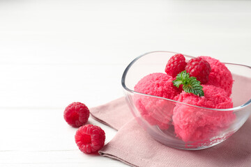 Delicious raspberry sorbet with mint in bowl, napkin and fresh berries on white wooden table, closeup