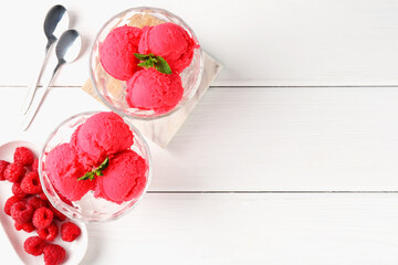 Delicious raspberry sorbet with mint in dessert bowls, spoons and fresh berries on white wooden...