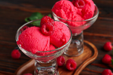 Delicious raspberry sorbet in dessert bowls and fresh berries on wooden table, closeup