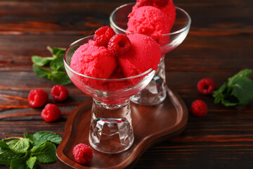 Delicious raspberry sorbet in dessert bowls, mint and fresh berries on wooden table, closeup