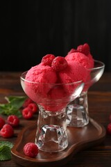 Delicious raspberry sorbet in dessert bowls, mint and fresh berries on wooden table against black...