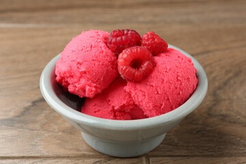 Delicious raspberry sorbet with fresh berries in bowl on wooden table, closeup