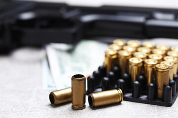 Bullets, gun and dollars on grey table, closeup