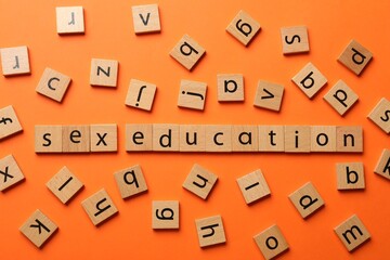 Words Sex Education made of wooden squares with letters on orange background, flat lay