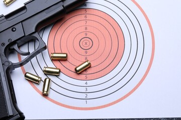 Many metal bullets and gun on shooting target, flat lay