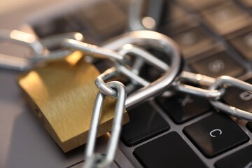 Cyber safety. Metal padlock with chain on laptop, closeup