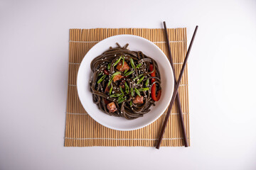 black pasta with vegetables on white background