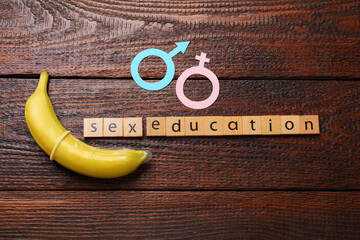 Phrase Sex Education made of wooden letters, banana with condom, paper female and male gender...