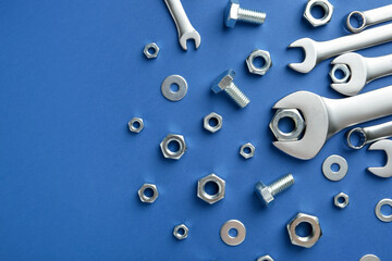 Metal wrenches, nuts and bolts on blue background, flat lay. Space for text