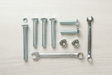 Metal wrenches, nuts and bolts on white wooden table, flat lay
