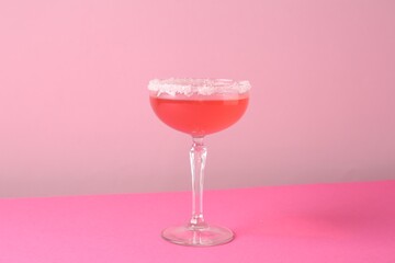 Martini cocktail with sugar in glass on pink background