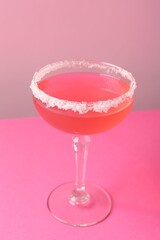 Martini cocktail with sugar in glass on pink background, closeup