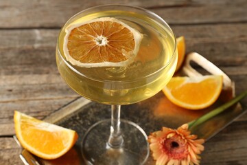 Martini cocktail in glass, orange slices and flower on wooden table, closeup