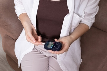 Close up of woman using glucometer to check blood sugar level. Concept of diabetes control, glucose...