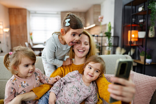 Mother and her three little daughters taking selfies at home