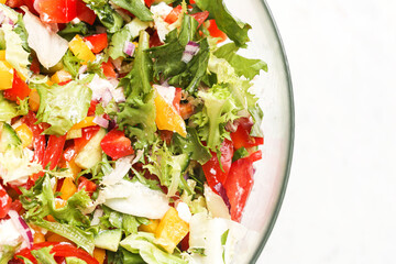 Fresh vegetable salad in glass bowl. Colorful mix of lettuce, bell peppers, cucumber, onion and tomato. Healthy vegetarian meal. Top view closeup shot white background with empty copy space for text.