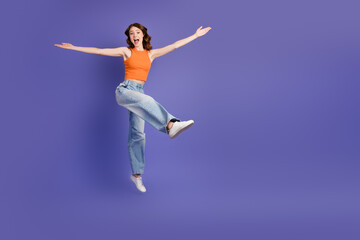 Obraz premium She is adorable and energetic in orange top and jeans on violet background showcasing youthful style and active lifestyle