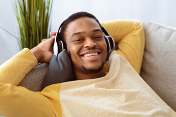 Closeup of relaxed black guy listening to music, using headset, copy space. Happy african american...
