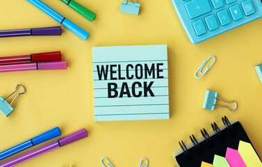 A yellow background with a green sign that says Welcome Back