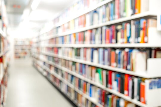 Blurry or blurred image of bookshelves inside a public library. Wide angle, diminishing perspective, shallow depth of field, blurry background, no people