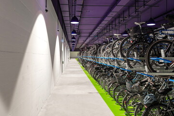 Many rows of bicycles stacked inside underground public bike parking place. Wide angle view,...