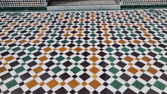 Moroccan architecture. Floor and wall covered in colorful geometric tiles adorn a building with a large door featuring intricate Arabic-style wood carving. Ideal for themes of architecture, decoration