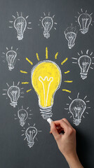 Hand drawing a bright yellow light bulb idea surrounded by chalk sketches on a blackboard graphic