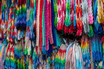 In a Buddhist temple, delicate origami cranes (orizuru) hang as offerings—each crane embodying a...