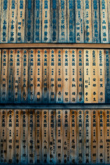 Wooden ema prayer plaques with handwritten wishes hanging in a Japanese Buddhist temple, symbolizing faith, devotion, and the spiritual tradition of offering prayers for good fortune.