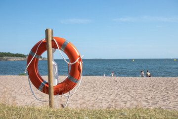 Lifebuoy lying on sandy beach by the sea. Maritime safety and rescue equipment, symbol of SOS and protection in coastal environment during summer