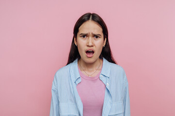 Young woman with surprised expression against pink background.