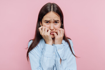 Worried Woman Biting Nails Against Pink Background