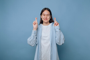 Young woman with closed eyes crossing fingers for luck.