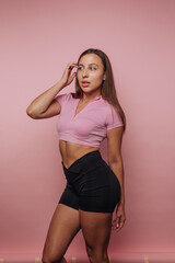 Obraz premium Woman in athletic wear posing against a pink background.
