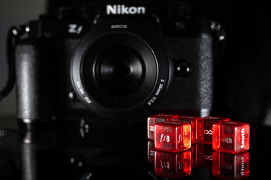 Doha, Qatar - August 22, 2025: Close-up of Red Photography Dice and Nikon Camera on isolated background